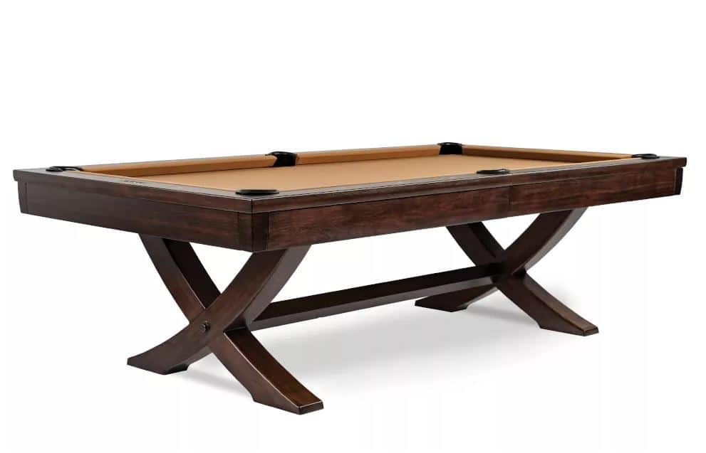 Dark wood pool table with beige felt, six pockets, and curved cross-legged supports.